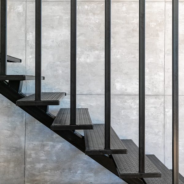 Loft minimal interior with metallic staircase on the background of gray cement wall.